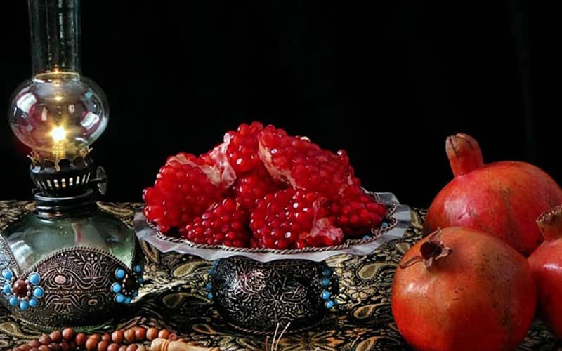 انار درسته و دون شده در کنار چراغی کوچک