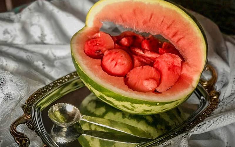 یک هنداونه نصفه با چند اسکوپ هندوانه روی آن