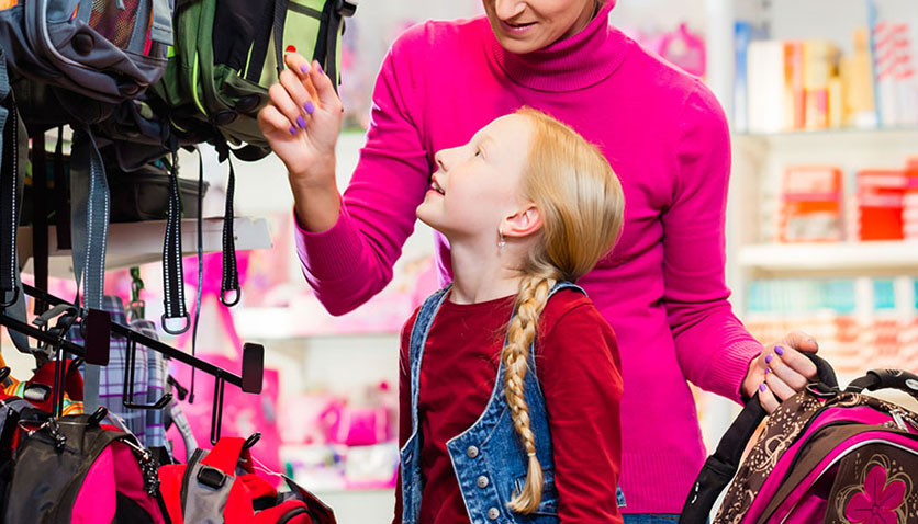 والدین و کودک در حال انتخاب و خرید لباس از فروشگاه